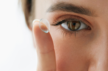 Das Bild zeigt das Auge einer Frau und den Zeigefinger mit einer Linse.